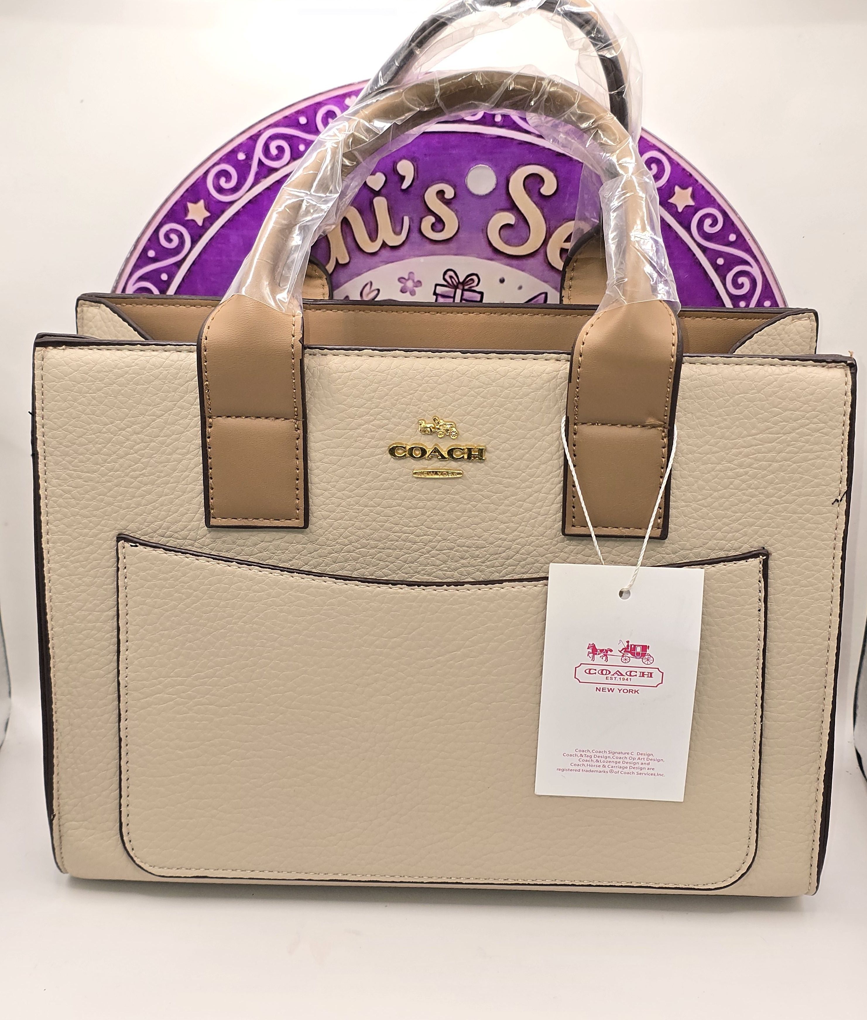 Bi14 Bolsa Coach Beige con vivos color camello. Incluye muñequera y strap para usar como crossbody